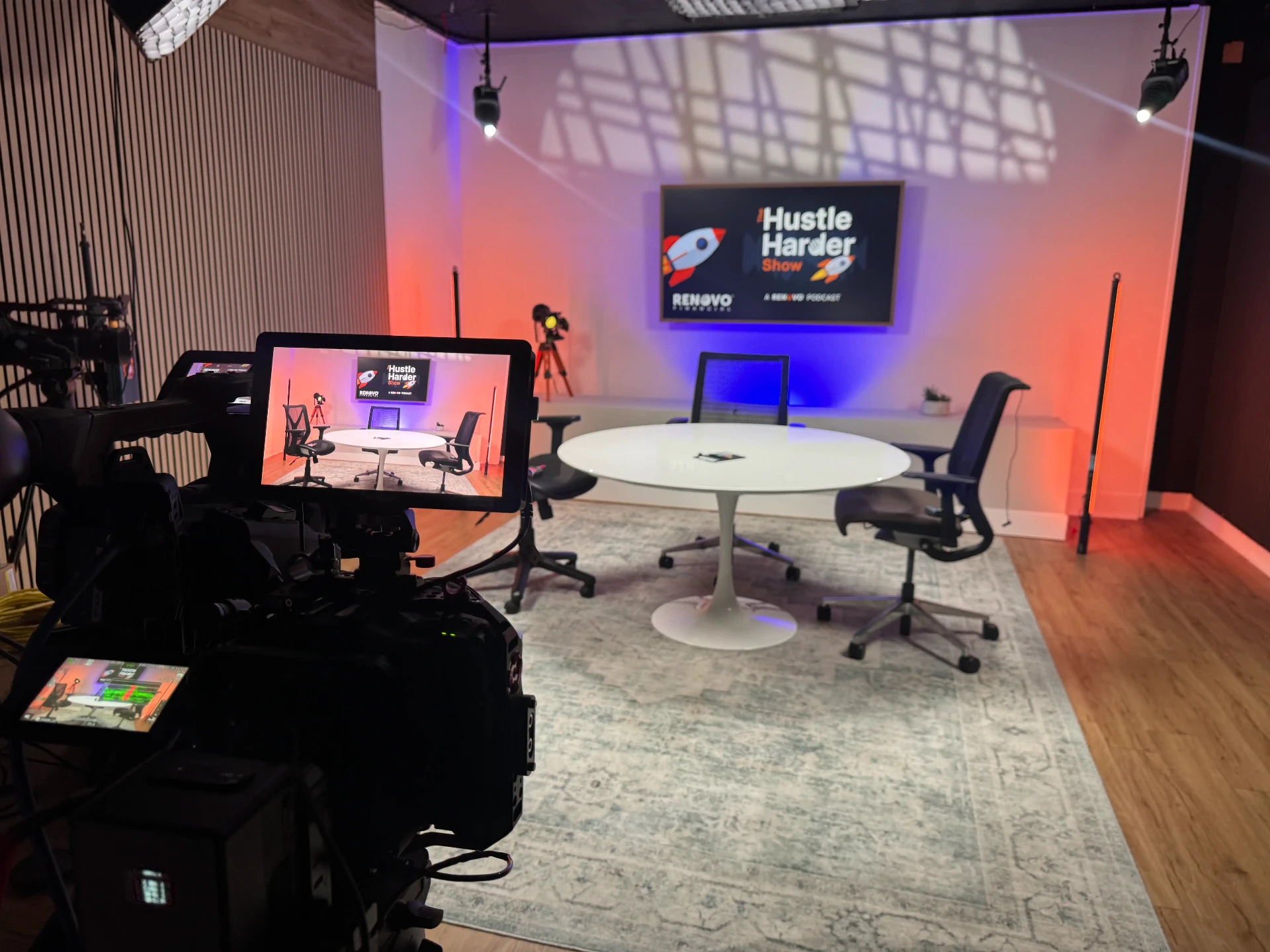 Round table podcast set lit in orange and blue with cameras at Lobi Space Chicago