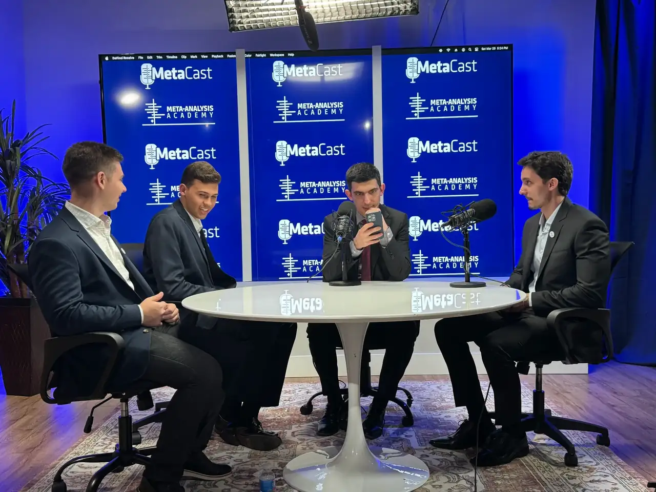 Four guests recording a panel podcast at a round table with boom microphones in the Lobi Space studio