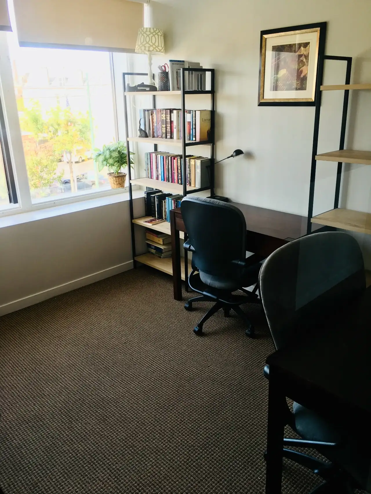 Bright private office with a wooden desk, bookshelf and tall window overlooking the street at Lobi Space Chicago