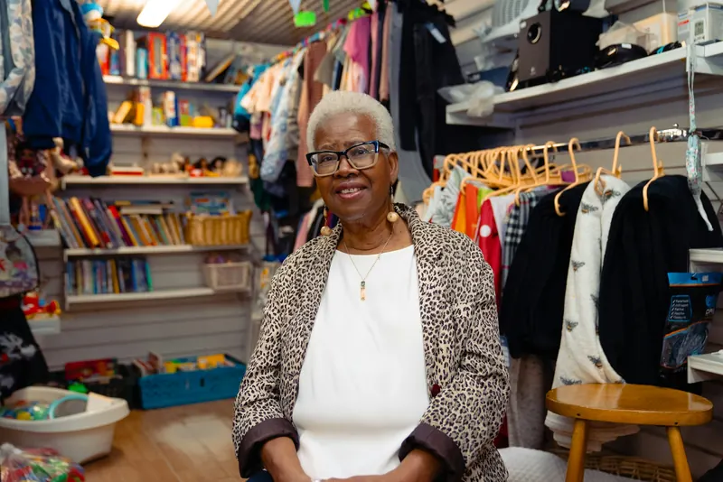 Shop owner smiling in her small clothing and book shop
